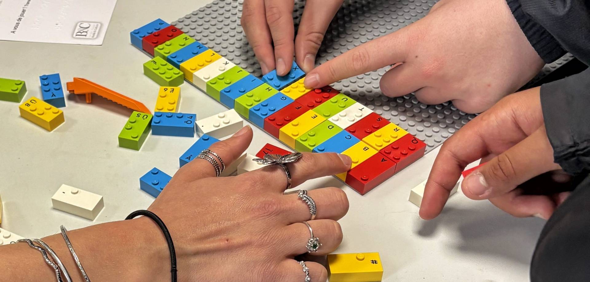 Des mains sur des lego braille